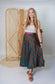 Woman wearing a patterned skirt standing in front of a bamboo screen.