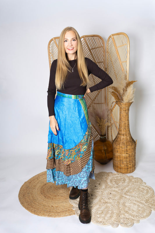 Woman wearing a blue skirt with a patterned hem standing in front of decorative elements.